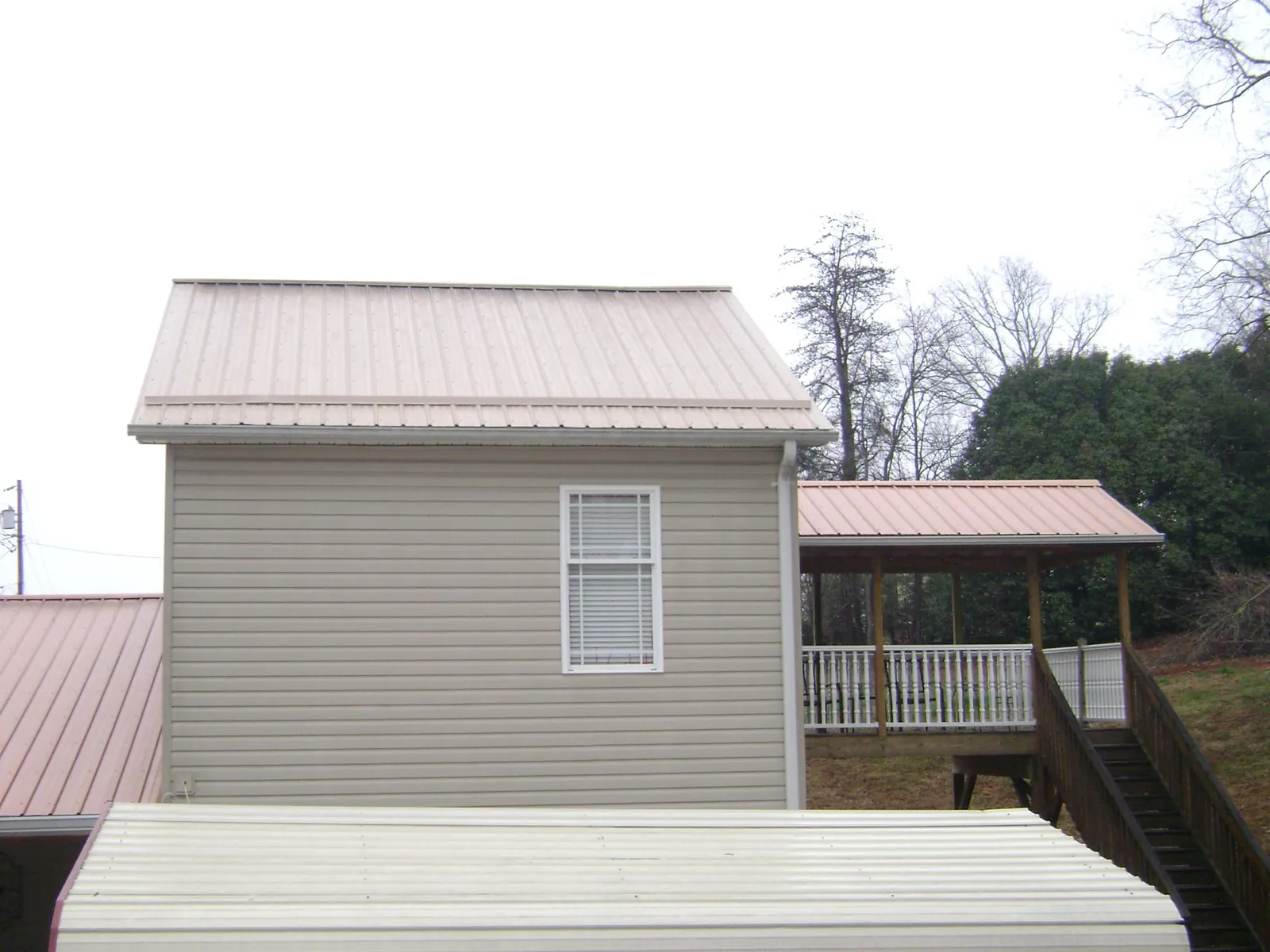 Tan metal roofs on a two story addition and attached porch, from a Roof Replacement job in Nashville